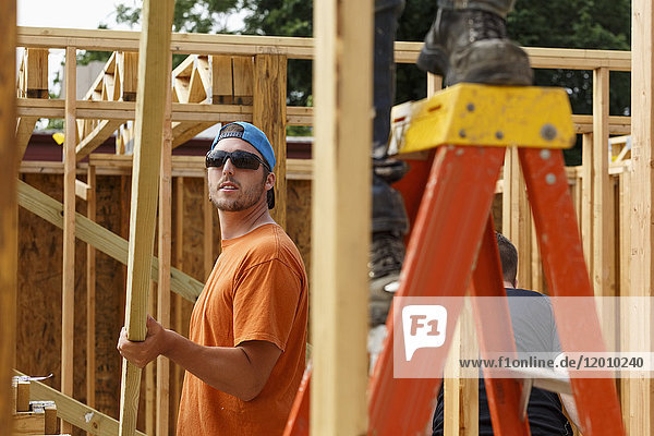 Caucasian man lifting lumber at construction site
