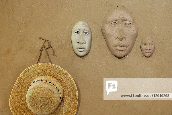 Clay masks and hat hanging on wall