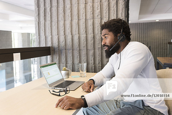 Black man wearing headset using laptop