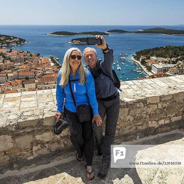 Kaukasisches Paar posiert für Handy-Selfie mit malerischem Blick auf den Ozean