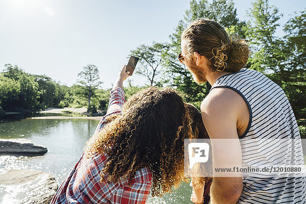 Freunde posieren für ein Handy-Selfie am Fluss