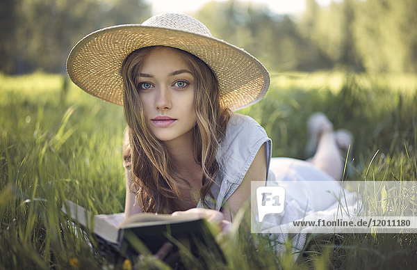 Kaukasische Frau liegt im Gras und liest ein Buch