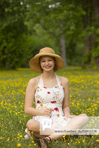 Caucasian teenage girl sitting in field of flowers