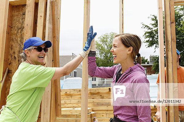 Caucasian volunteers high-fiving at construction site