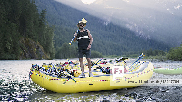 Mann hält Ruder  während er auf dem Floß am Flussufer steht  Squamish  British Columbia  Kanada