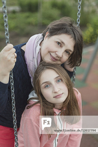Porträt einer älteren Frau mit Enkelin auf der Schaukel auf dem Spielplatz