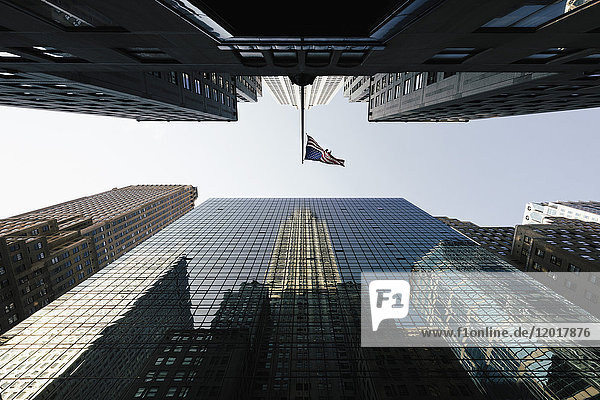 Direkt unter dem Blick auf American Flag inmitten moderner Bürohochhäuser gegen den Himmel  New York  USA