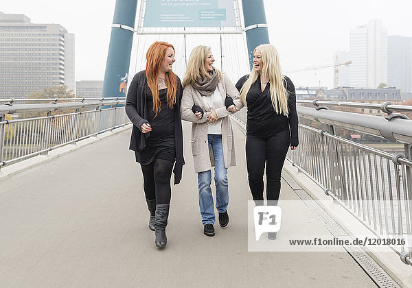 Drei Frauen überqueren eine Brücke