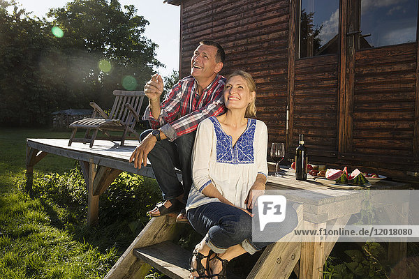 Smiling couple looking up while having wine outside farmhouse