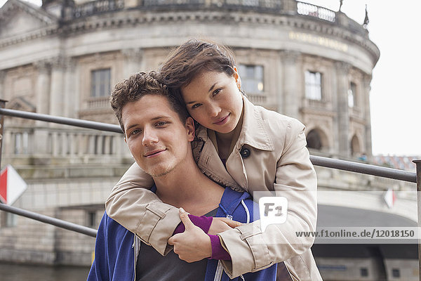 Low angle portrait of woman embracing male friend against Bode Museum  Berlin  Germany