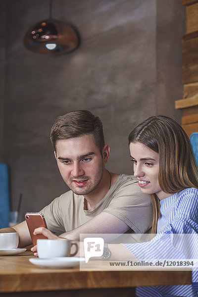 Young couple using mobile phone while sitting at restaurant