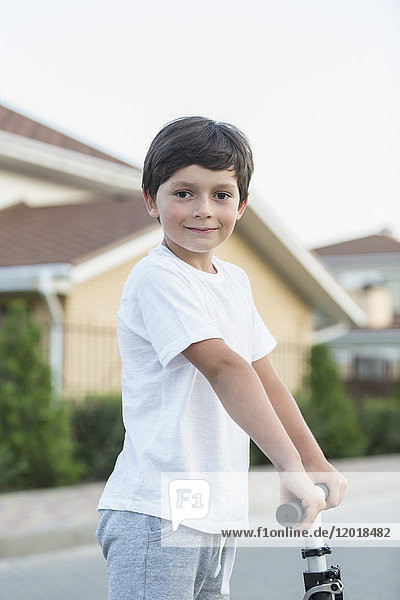 Portrait des Jungen mit Roller in der Stadt