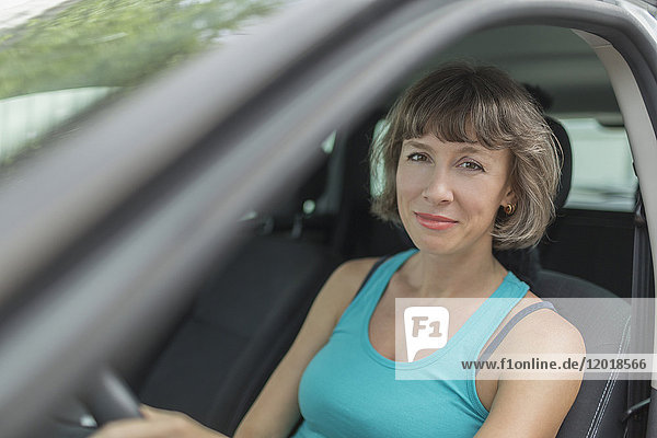 Porträt der lächelnden reifen Frau im Auto sitzend