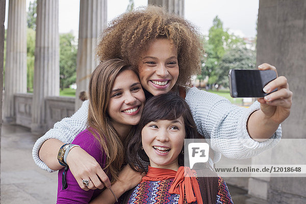 Smiling young woman taking selfie with female friends