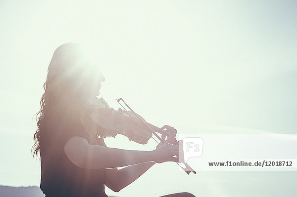Niederwinkelansicht einer Frau  die an einem sonnigen Tag Geige spielt.