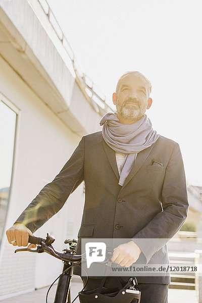 Low angle view of businessman with bicycle in city on sunny day