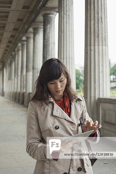 Junge Frau mit digitalem Tablett beim Gehen im Flur  Berlin  Deutschland