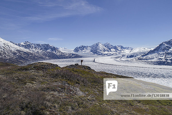 Full length of hiker looking at glacier against blue sky  Knik Glacier  Palmer  Alaska