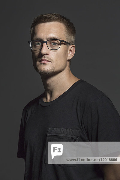 Portrait of mid adult man wearing eyeglasses standing against gray background