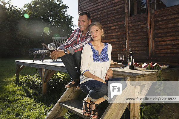 Ein reifes Paar genießt den Wein  während es vor dem Bauernhaus sitzt.