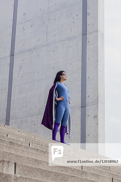 Niedriger Blickwinkel des weiblichen Superhelden  der auf einer Treppe an der Wand steht.