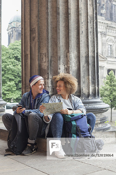 Lächelnder junger Tourist sitzend mit Karte im Alten Museum  Berlin  Deutschland