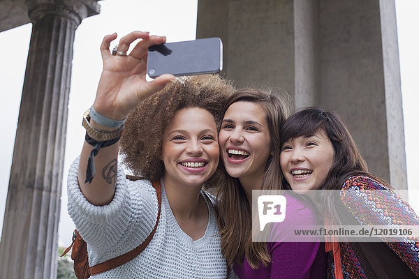 Niedriger Blickwinkel auf lächelnde junge Freundinnen  die Selfie nehmen.