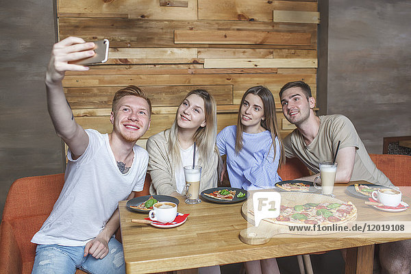 Junge Freunde  die im Restaurant sitzen und Selfie nehmen