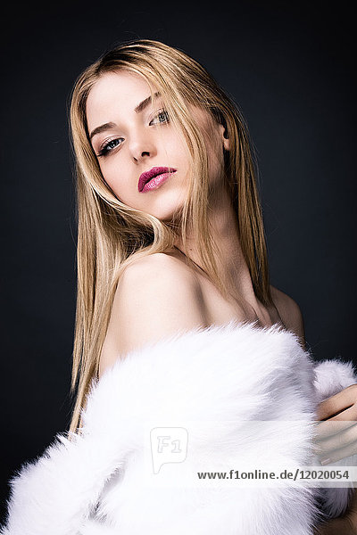 Porträt einer sinnlichen jungen Frau in einem weißen Pelzmantel
