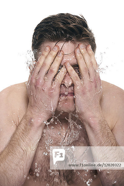 Oben-ohne-Mann  Wasser auf sein Gesicht spritzend  Gesicht in den Händen  Augen geschlossen