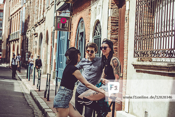 Three young people chatting in the street  cityscape
