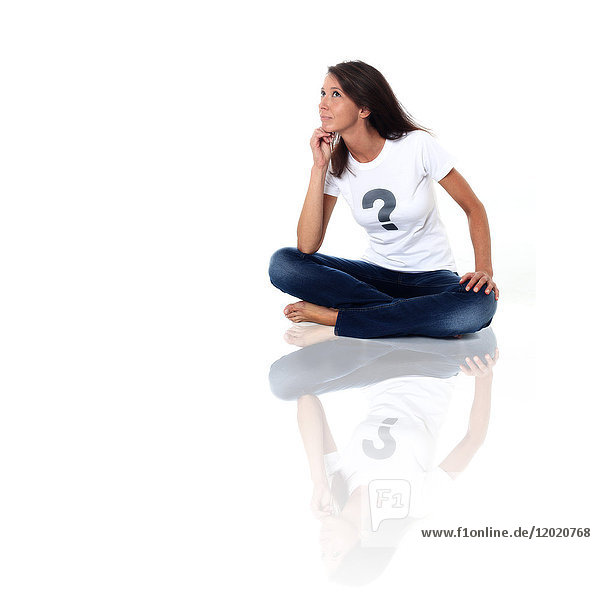 'Brown woman in studio wearing a tee shirt with a question mark and pensive air. Conceptual image on the theme ''Born under X'''