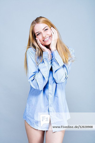 Porträt einer lächelnden jungen Frau  Hemd  Hände auf den Wangen  Blick auf das Ziel gerichtet