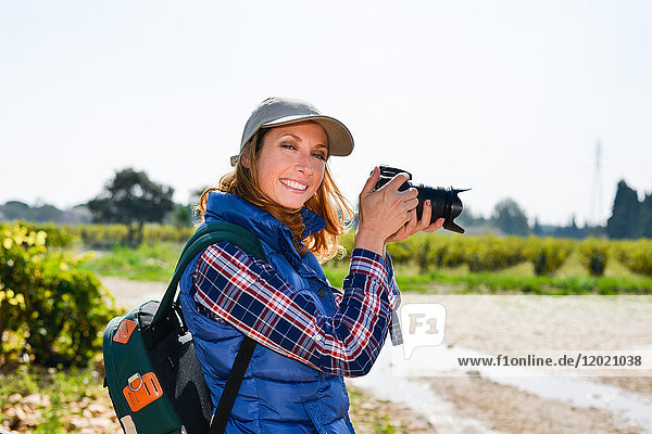 cheerful young woman hiking and taking pictures with her reflex single lens camera- Cepage Grenache  Chateauneuf du Pape  cotes du Rhone  France