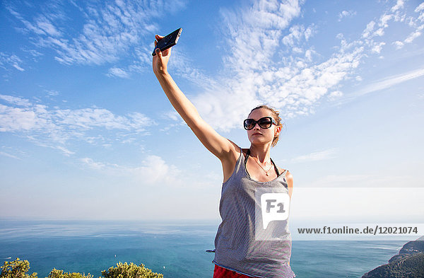 Porträt einer jungen Frau  die ein Selfie mit ihrem Smartphone auf den Höhen von Setubal  Lissabon und Umgebung  Portugal  macht