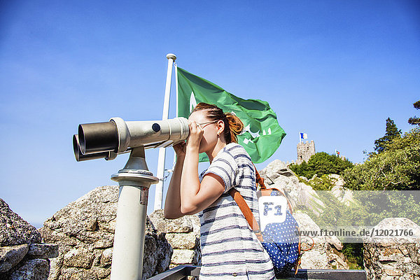 Porträt einer jungen Frau im Profil  die auf das Binokularteleskop an den Wänden der maurischen Burg blickt  Sintra  Region Lissabon  Portugal