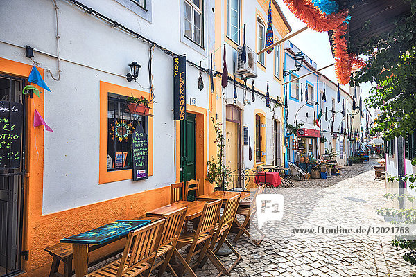 Restaurantterrassen in einer gepflasterten Straße des Dorfes Ferragudo  Region Algarve  Portugal