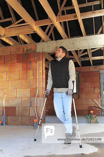 Frankreich  junger Arbeiter mit Krücken in einem Haus im Bau.