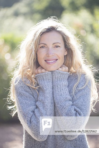 Porträt einer lächelnden jungen blonden Frau mit einem großen Pullover.