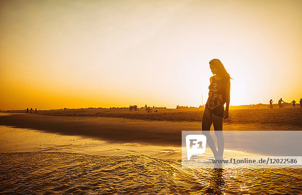 Junge Frau  die bei Sonnenuntergang am Strand Praia do Barril spazieren geht  Stadt deTavira  Region Algarve  Portugal