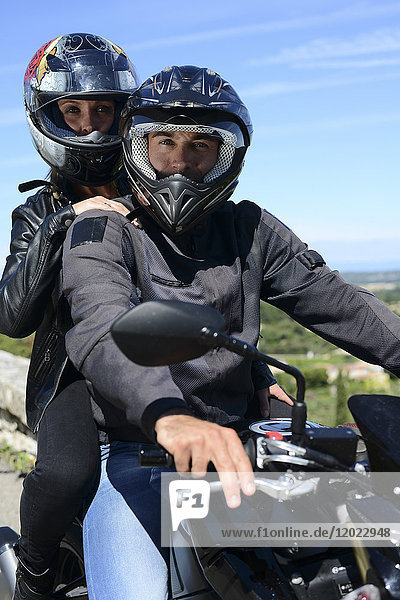 Happy young biker couple riding motorbike in summer.