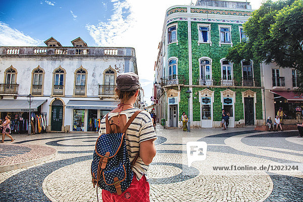 Junge Frau von hinten  beobachtet den Platz der Stadt Burgau  Region Algarve  Portugal