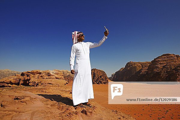 Beduine benutzt sein Smartphone am Felsbogen  Al Borg Alsagheer  Wadi Rum  Jordanien  Asien