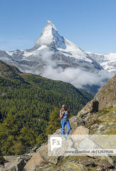 Hiker stands on rocks  snow-covered Matterhorn at the back  Valais  Switzerland  Europe