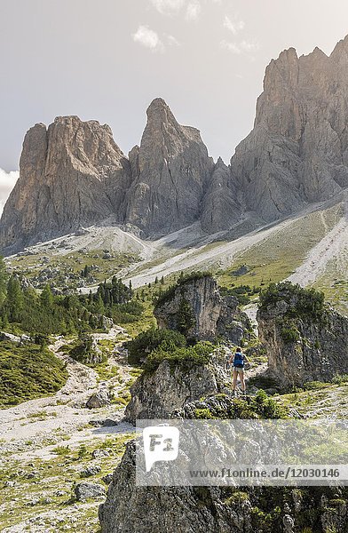 Hiker standing on rocks  scree field below the Geisler Peaks  behind the Geisler Group  Villnösstal Sass Rigais  Dolomites  South Tyrol  Italy  Europe
