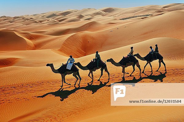Touristen auf Kamelritt vor hohen Sanddünen  Sandwüste  Rub Al Khali  Emirat Abu Dhabi  Vereinigte Arabische Emirate  Asien