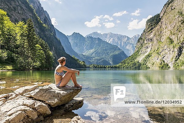Junge Frau sitzt in Badekleidung am Obersee  Watzmann und Bergkulisse  Berchtesgadener Alpen  Nationalpark Berchtesgaden  Oberbayern  Bayern  Deutschland  Europa