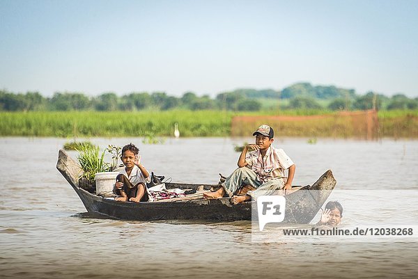 Einheimische Kinder winken auf Holzboot  schwimmendes Dorf  Bootsfahrt  Tonle Sap See  Kambodscha  Südostasien  Asien