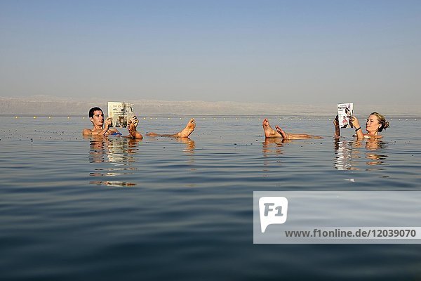 Young couple reads newspaper floating in Dead Sea  Jordan  Asia