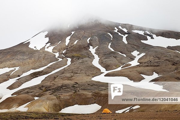 Ein Zelt an einem teilweise mit Schnee bedecktem Rhyolith-Berg  Hochtemperaturgebiet Hveradalir  Kerlingarfjöll  Island  Europa
